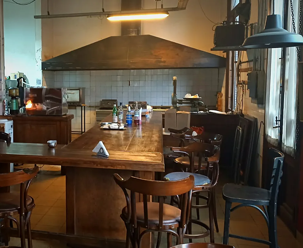 Barra larga de madera con banquetas y la campana de la cocina al fondo