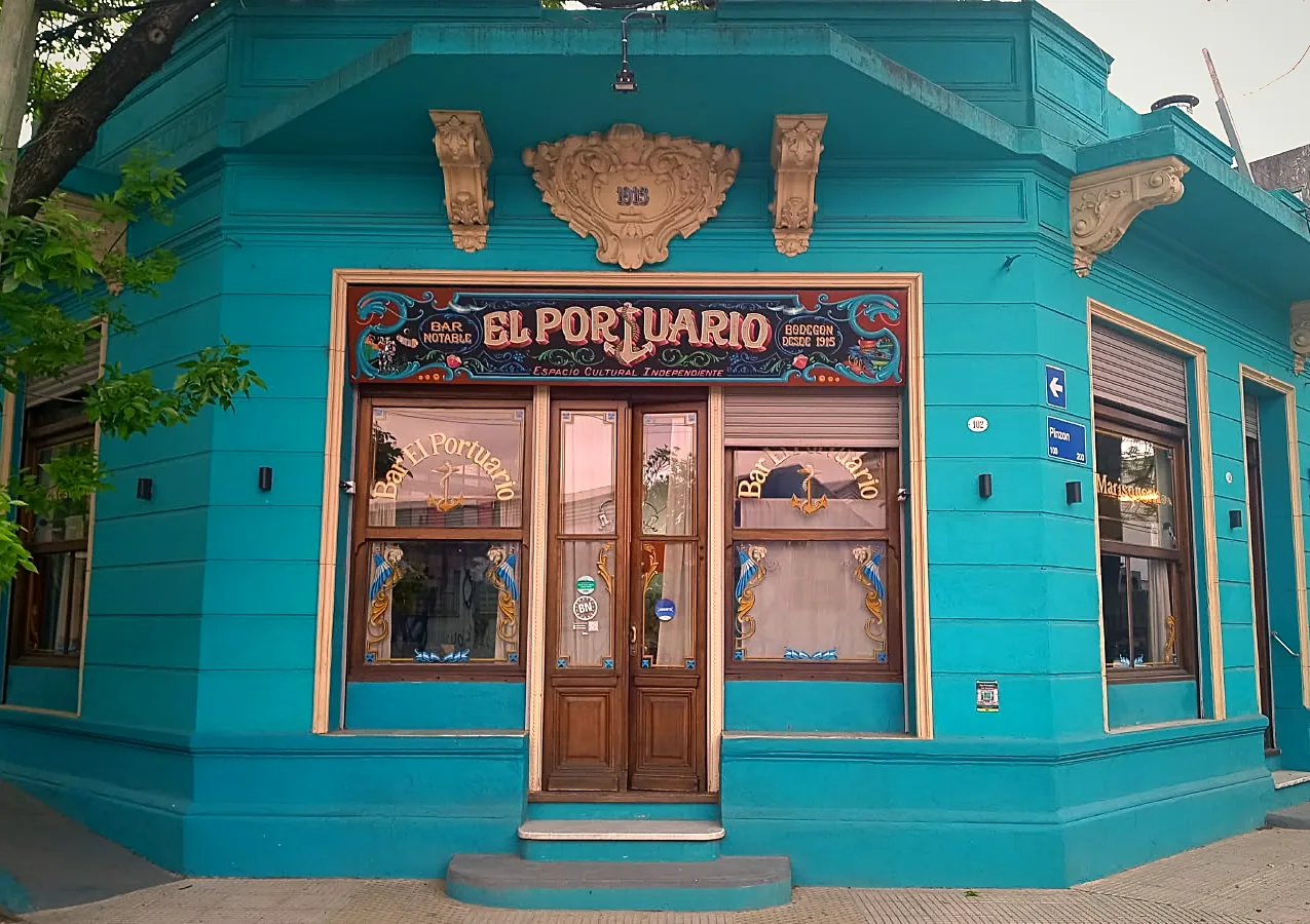 Fachada celeste del Bar El Portuario, con su cartel fileteado, en la esquina de Pinzón 102